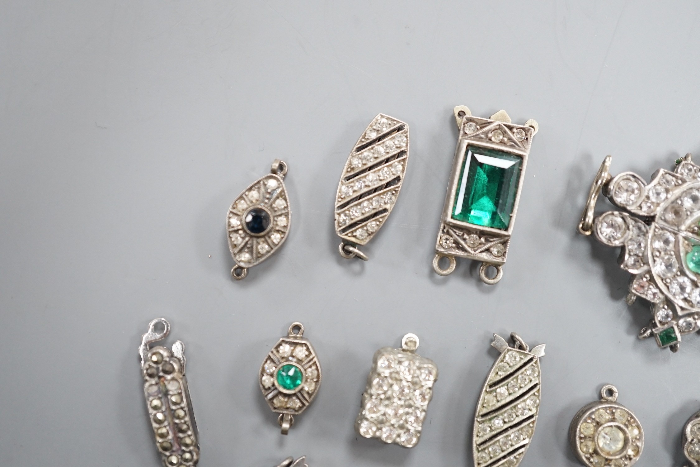 A small group of assorted white or base metal and paste set clasps.
